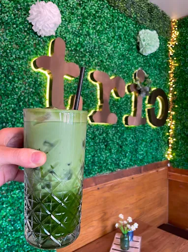Iced matcha in front of the Trio sign at Trio Cafe & Bar, York