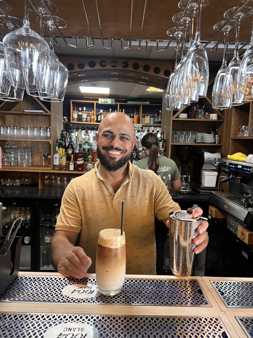 Emin, manager at Trio Cafe & Bar in York, serving an iced coffee at the bar